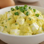 Cremiger Eiersalat in einer weißen Schüssel, garniert mit frischen Kräutern.